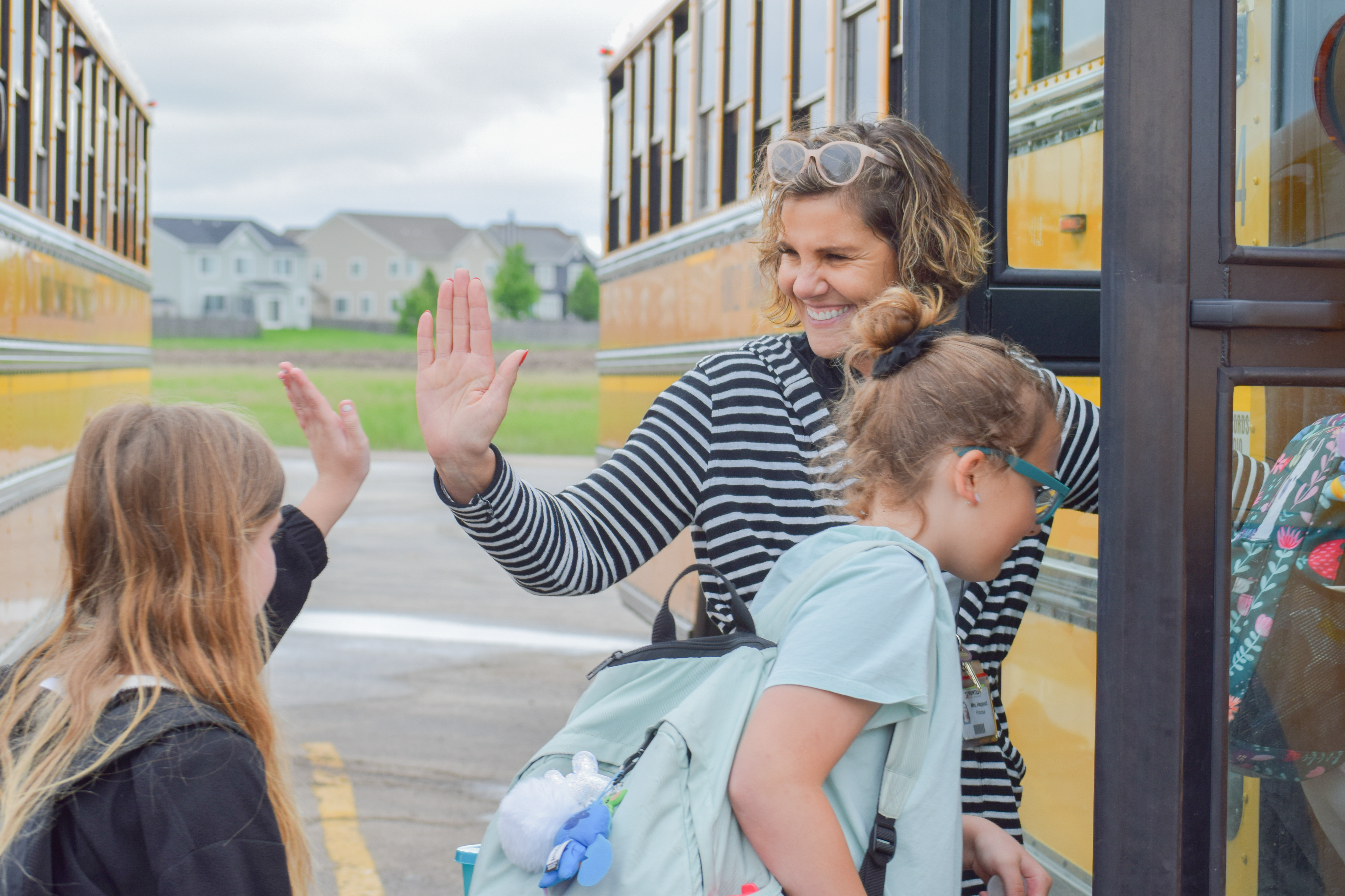 principal Michele Happold high-fiving students as they get onto the bus