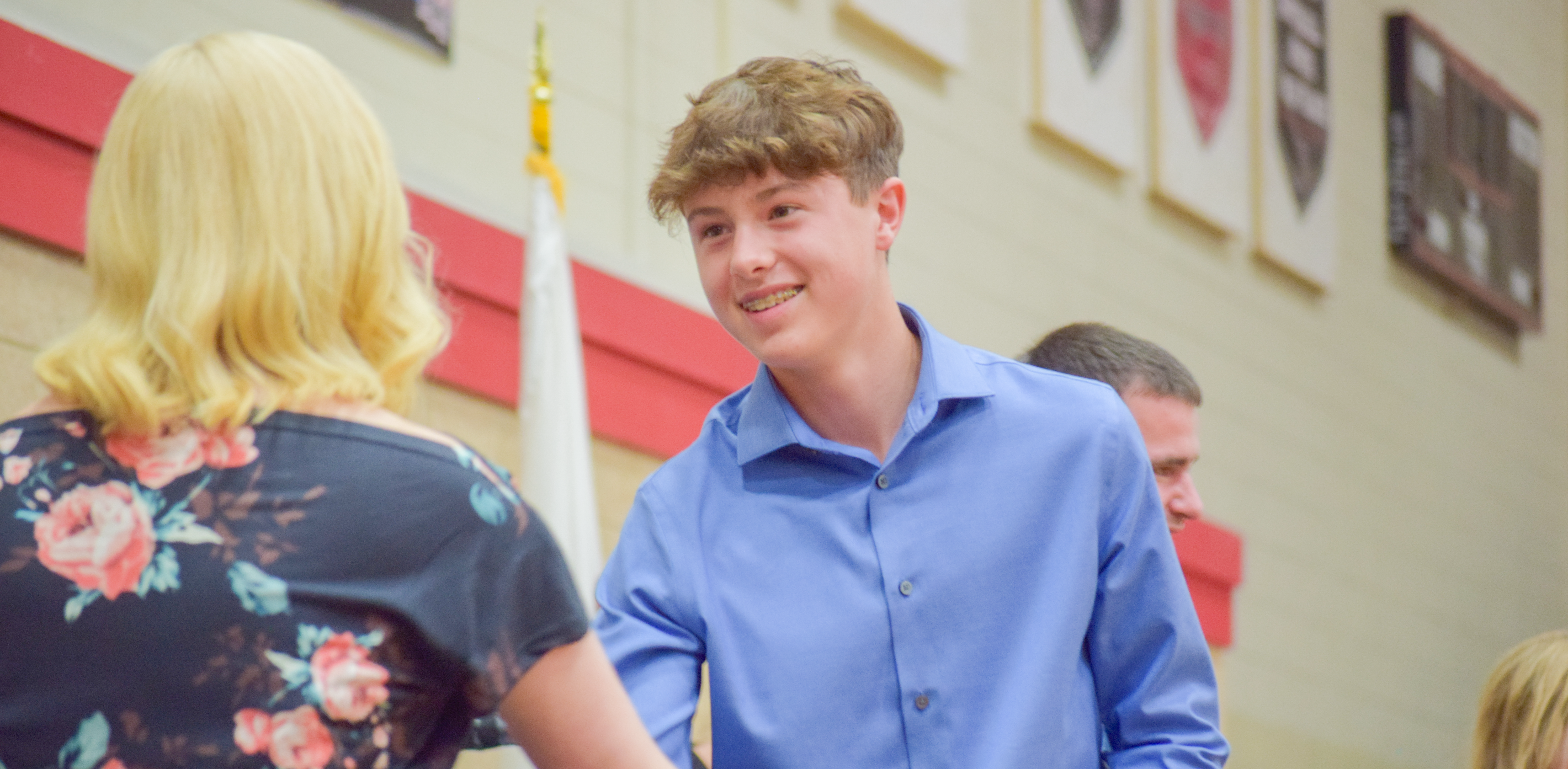 student shaking teacher's hand as he accepts diploma at eighth grade promotion